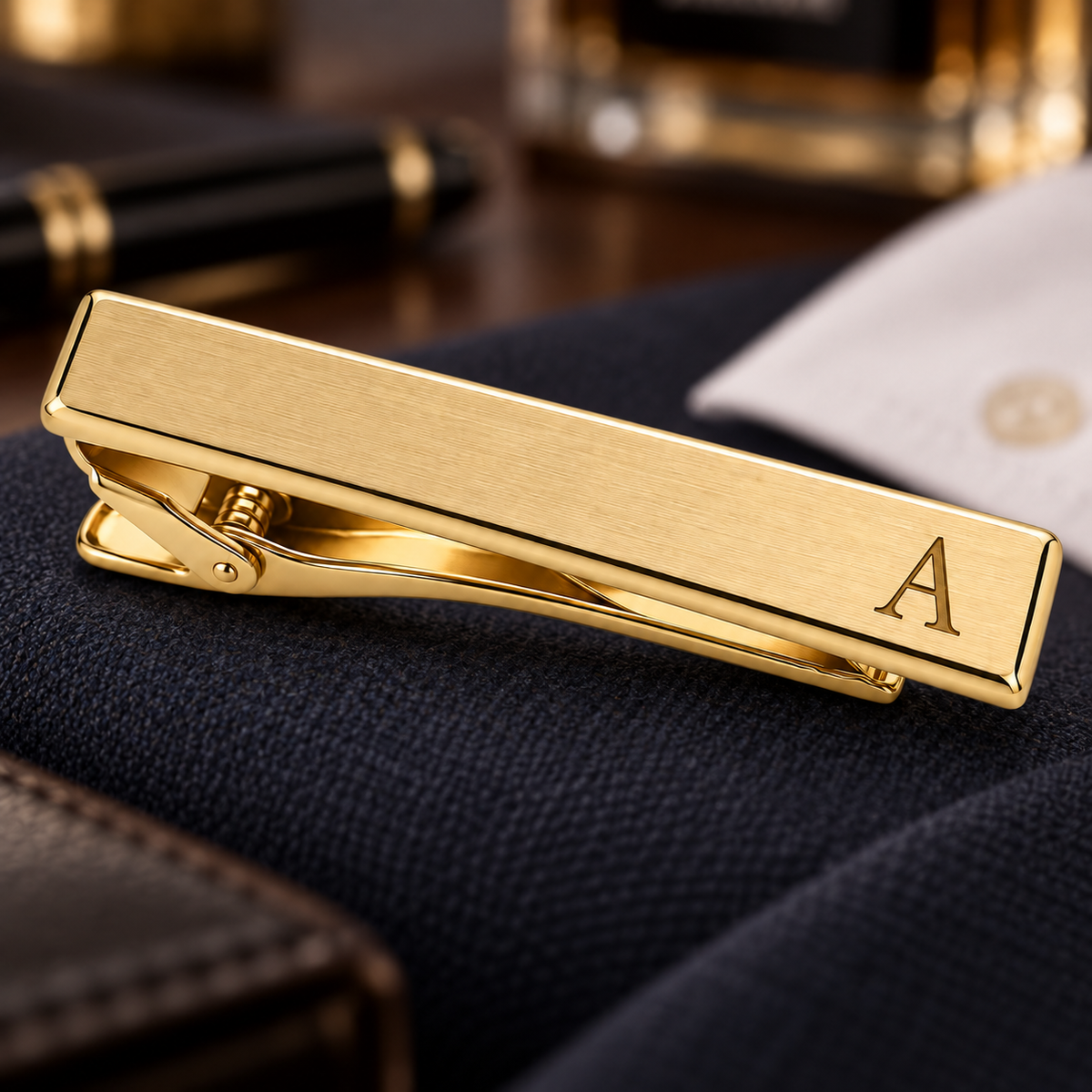 Brushed gold-tone rectangular tie clip with an engraved letter A at one end