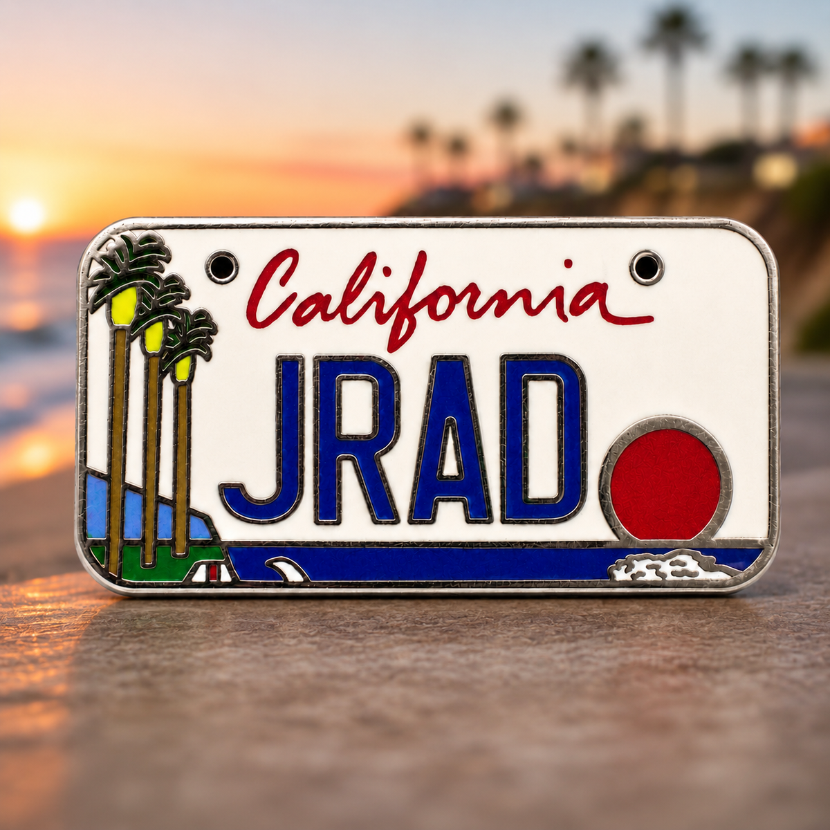 Silver-tone hard enamel pin styled as a California license plate with palm trees and a sunset