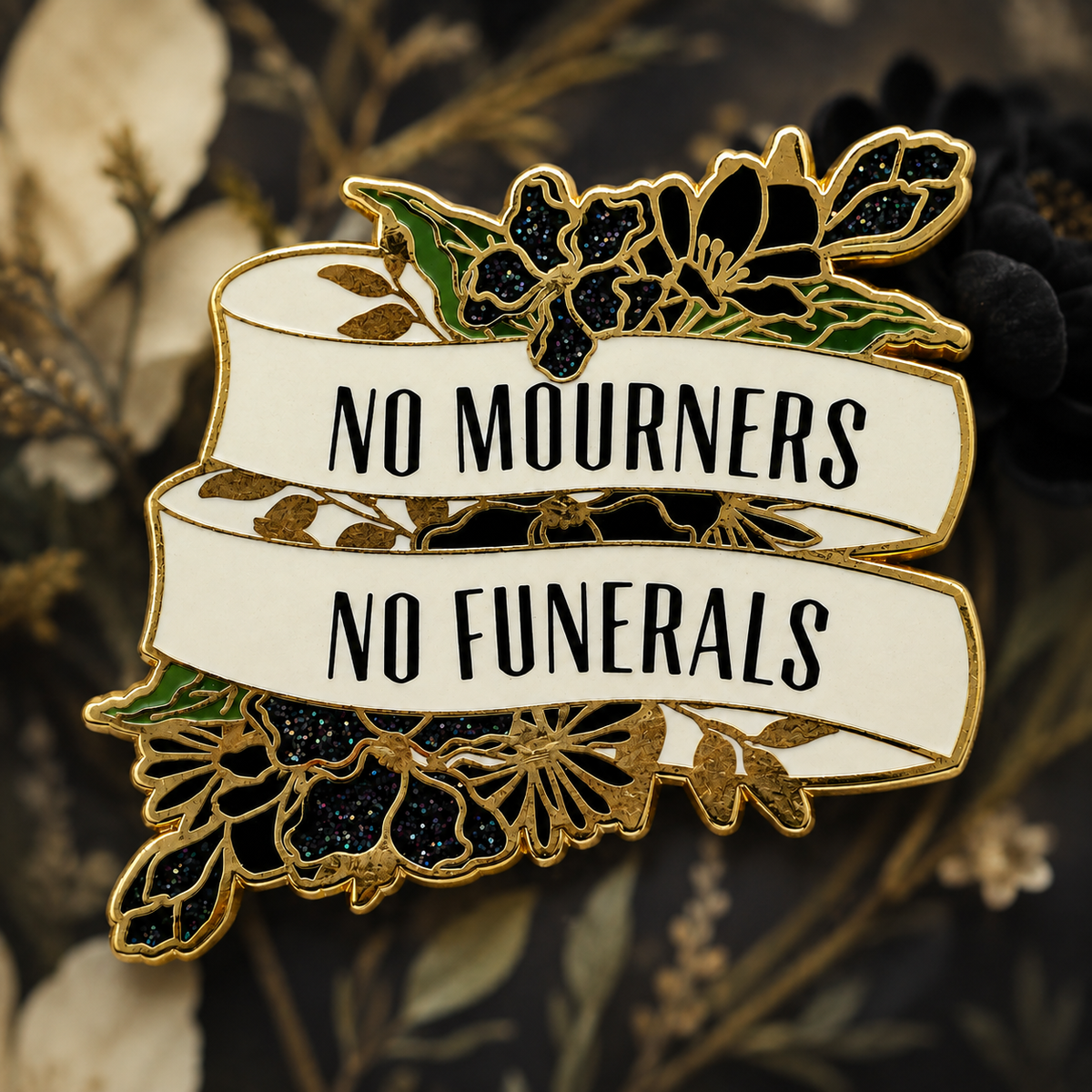 Gold-tone hard enamel pin with black glitter flowers and No Mourners No Funerals banners