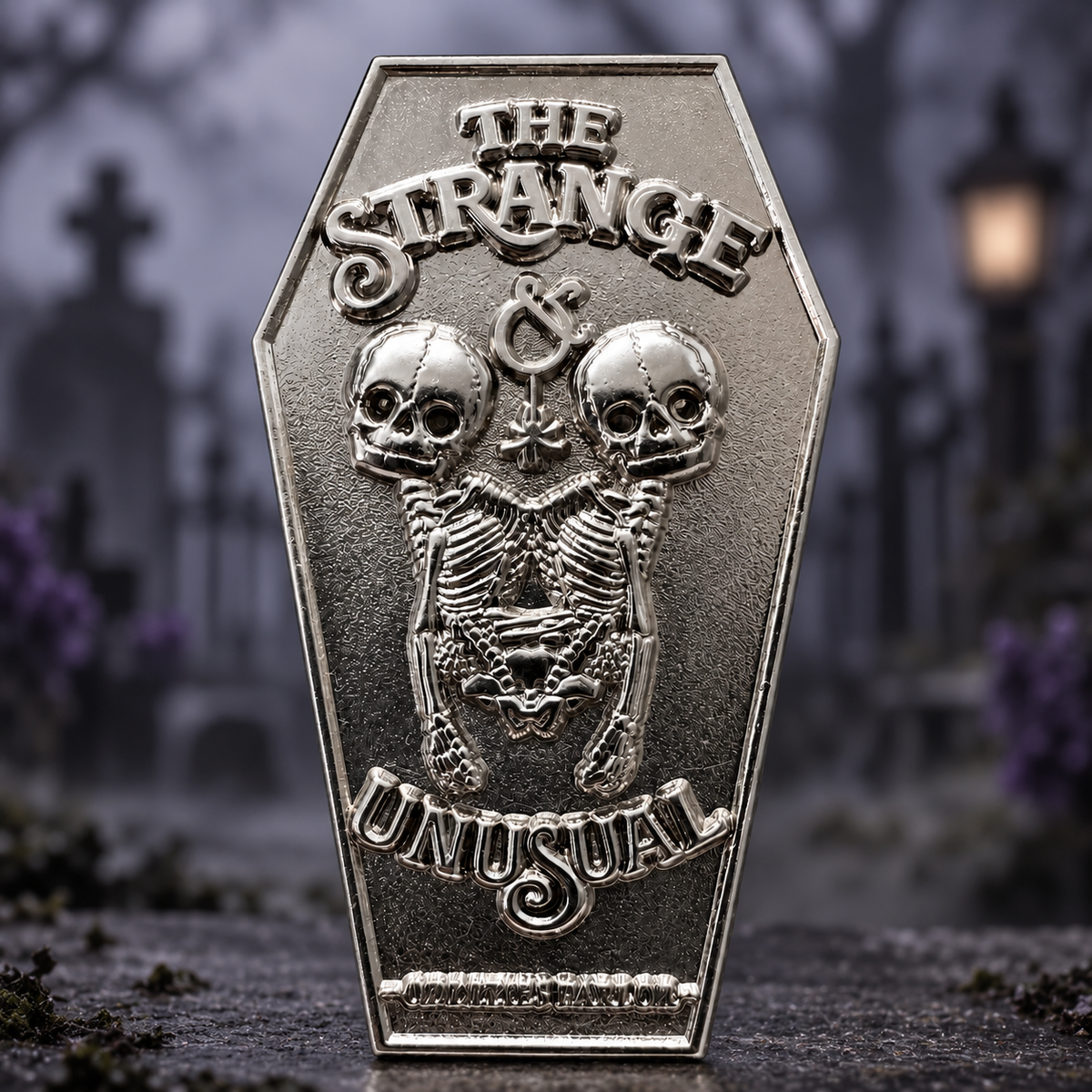 Twin skeletons and raised Strange and Unusual lettering fill a textured silver-tone coffin design