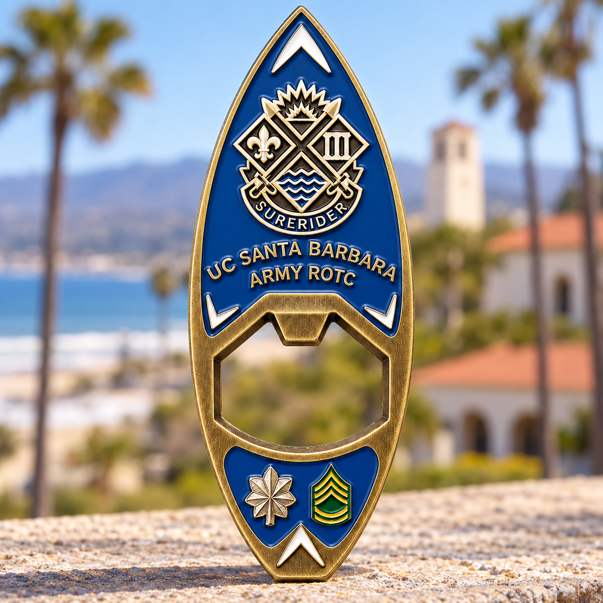 Blue and gold-tone surfboard-shaped UC Santa Barbara Army ROTC bottle opener with a central opening