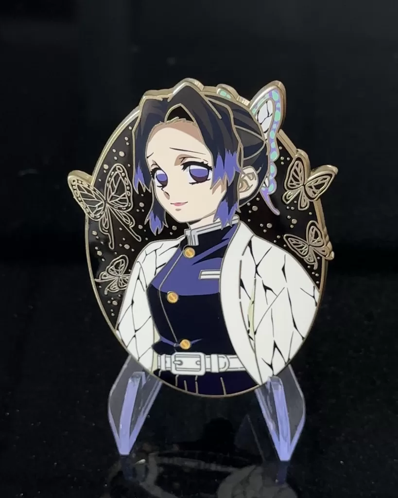 Custom soft enamel pin of Shinobu Kocho from Demon Slayer, featuring gold plating, screen printed butterfly patterns, and intricate detailing on a black backdrop.

